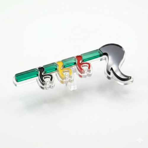 Broche Leawood en acrylique multicolore (vert, noir, jaune, rouge) en forme de queue de dragon stylisée du Doudou de Mons, présentée sur un support transparent.