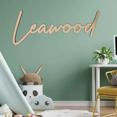 Prénom en bois "Leawood" de couleur bois naturel, accroché au mur vert d'une chambre d'enfant/bureau moderne