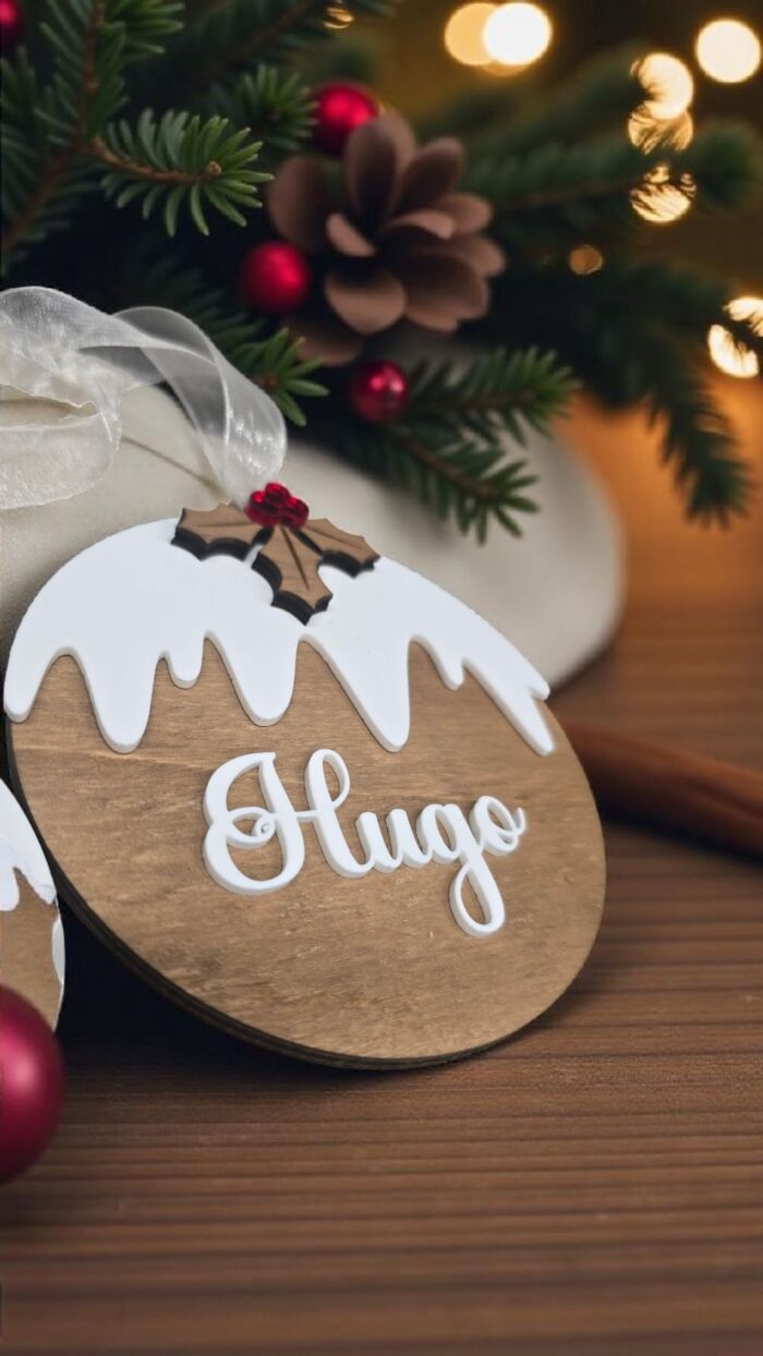 Boule de Noël en bois personnalisée avec le prénom Hugo dans sa pochette cadeau
