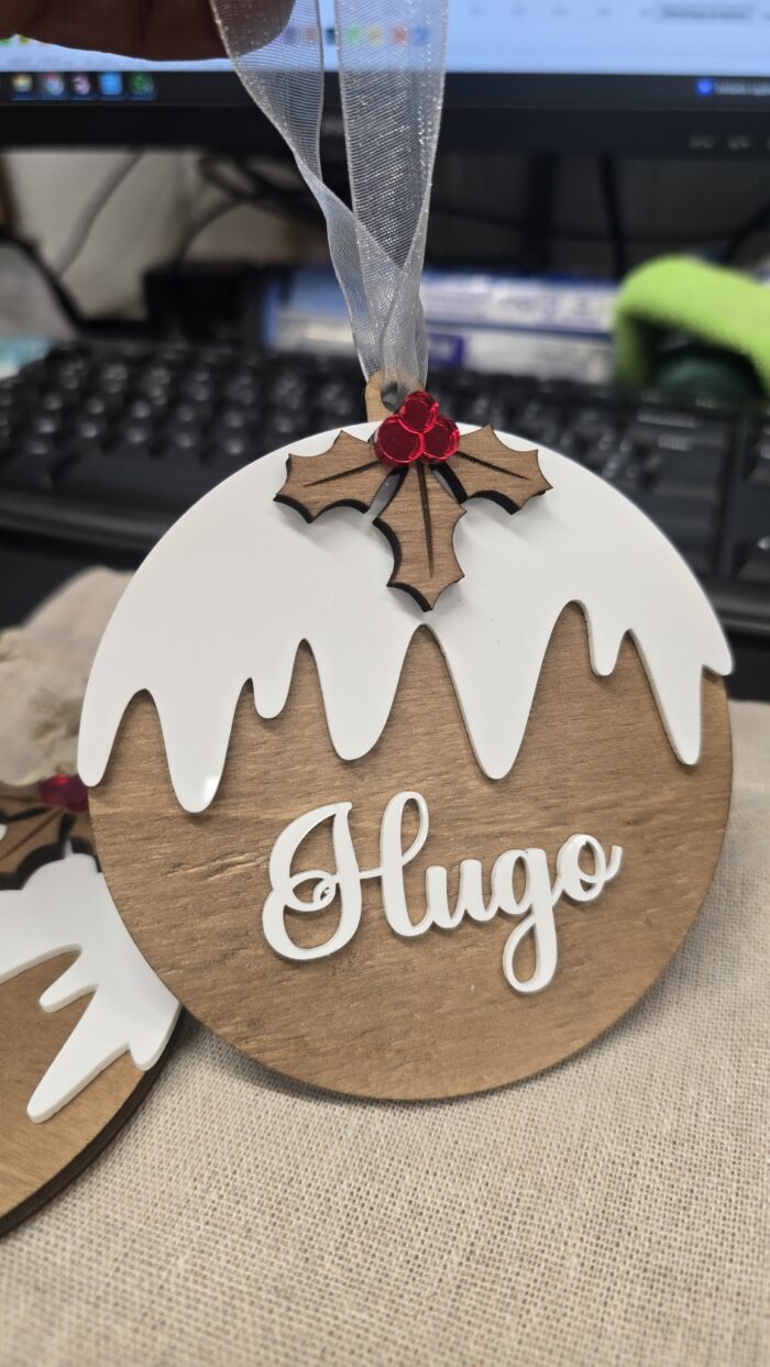 Boule de Noël en bois personnalisée avec le prénom Hugo dans sa pochette cadeau