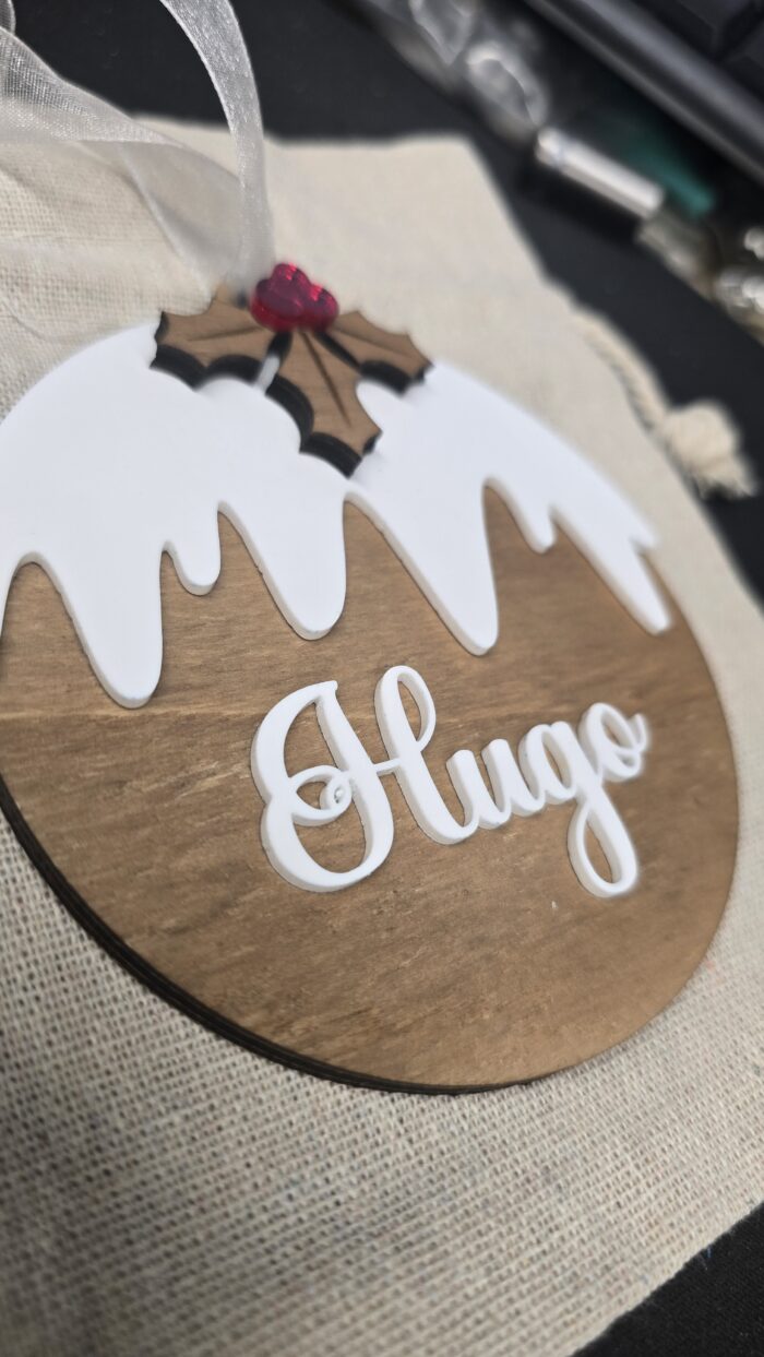 Boule de Noël en bois personnalisée avec le prénom Hugo dans sa pochette cadeau