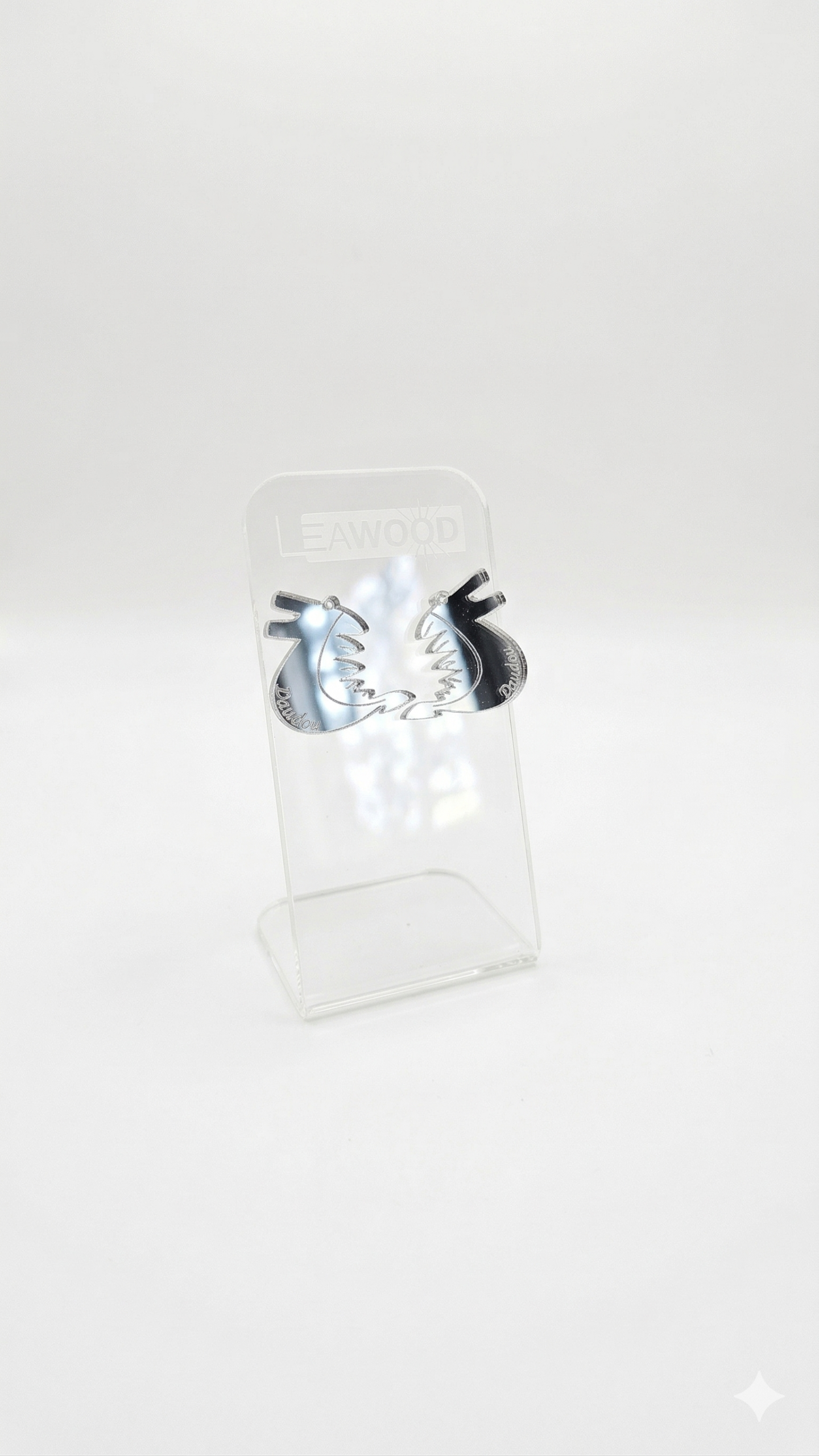 Paire de boucles d'oreilles dragon pour la Ducasse de Mons (Doudou) en acrylique miroir argenté, présentées sur un présentoir transparent LEAWOOD.