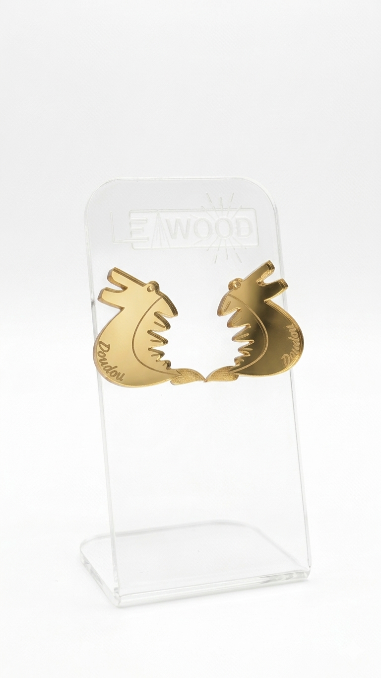 Paire de boucles d'oreilles en forme de dragon pour le Doudou de Mons, couleur doré en acrylique miroir, présentées sur un support transparent gravé LEAWOOD.