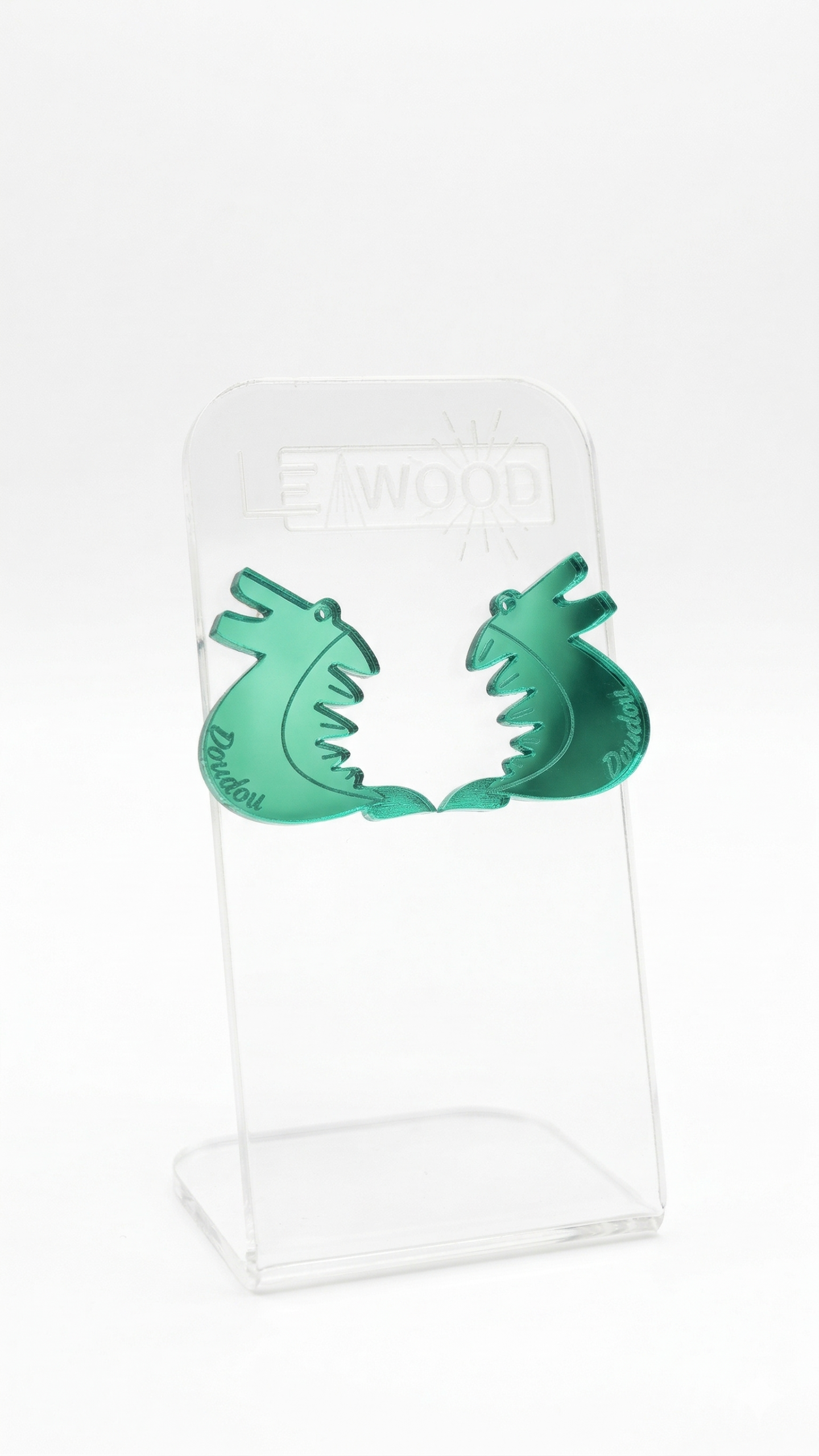 Paire de boucles d'oreilles en forme de dragon pour le Doudou de Mons, couleur vert émeraude en acrylique miroir, présentées sur un support transparent gravé LEAWOOD.