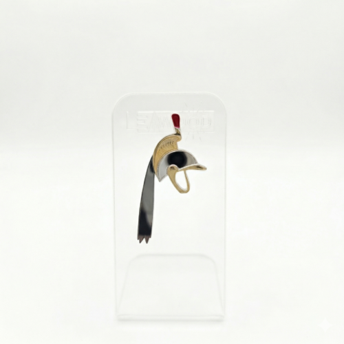 Pin's en acrylique miroir doré et argenté représentant le casque de Saint-Georges du Doudou de Mons, avec plumet rouge, sur présentoir transparent.