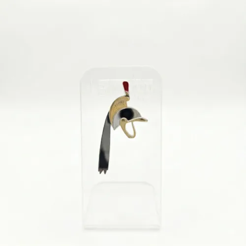 Pin's en acrylique miroir doré et argenté représentant le casque de Saint-Georges du Doudou de Mons, avec plumet rouge, sur présentoir transparent.